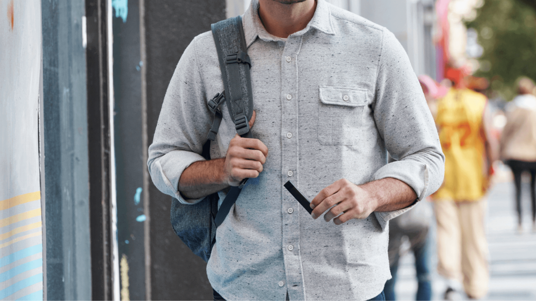 Man with backpack walking while holding a PAX Pod